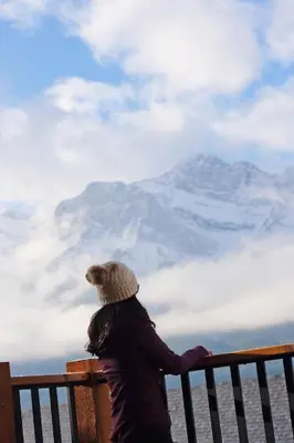 a person sitting on a bench looking at a mountain at Top FL 2BR 2BA Hot Tubs phenomenal mountain views in Canmore