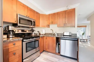 a kitchen with wooden cabinets and a stove top oven at Gondola Heights by Outpost Whistler in Whistler