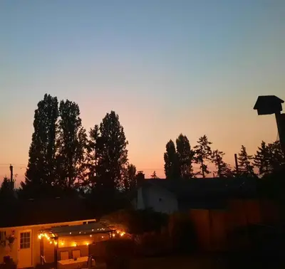 a sunset over a building with lights in front of trees at Simply Suite - Sua Casa Longe de Casa in YYJ