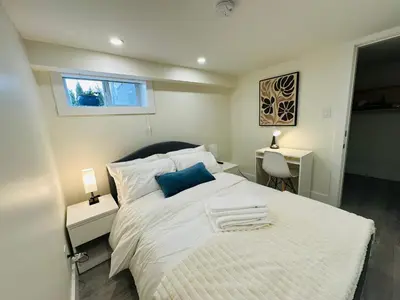 a bedroom with a large white bed with a blue pillow at Quiet Basement Suite Steps from Quilchena Park in Vancouver in Vancouver