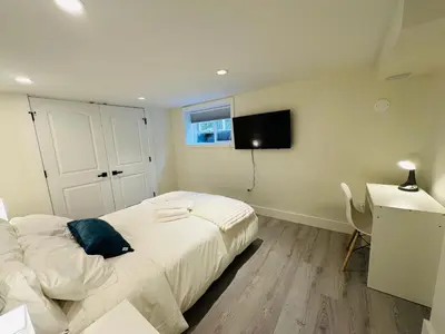 a bedroom with a bed and a desk and a television at Quiet Basement Suite Steps from Quilchena Park in Vancouver in Vancouver