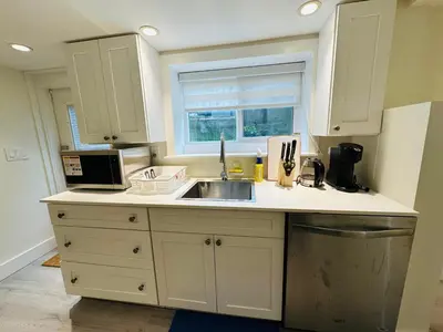 a kitchen with white cabinets and a sink and a window at Quiet Basement Suite Steps from Quilchena Park in Vancouver in Vancouver