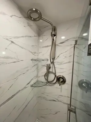 a bathroom with a shower with white marble walls at Passage view in Campbell River