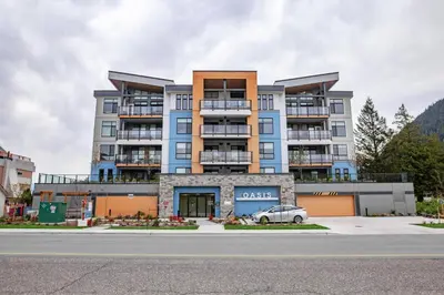 a large apartment building with a car parked in front at 2 Bedroom with Lake and Mtn Views in Harrison Hot Springs