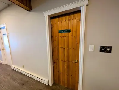 a room with a wooden door with a sign on it at Purcell Condos by StayIn in Kimberley