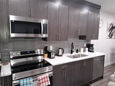 a kitchen with a stainless steel stove and a microwave at Cozy 2 Bedroom Walkout Basement in Calgary