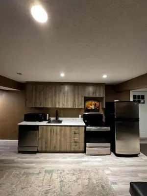 a kitchen with wooden cabinets and a black refrigerator at Cozy and Spacious Basement in Chestermere