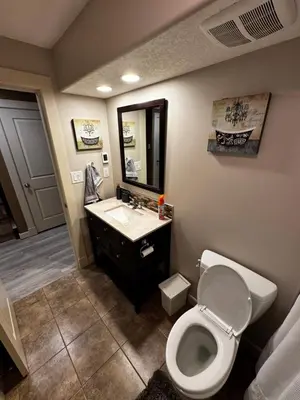 a bathroom with a toilet and a sink and a mirror at Cozy and Spacious Basement in Chestermere