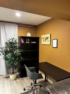 a office with a black desk and a plant at Cozy and Spacious Basement in Chestermere