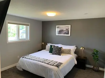 a bedroom with a large white bed with a window at Spacious Drumheller-RetreatMuseum & Golf in Drumheller