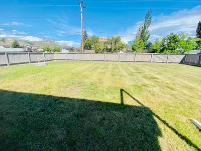 a yard with a fence and a large grass field at Spacious Drumheller-RetreatMuseum & Golf in Drumheller