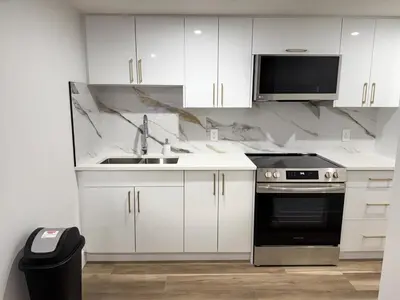 a kitchen with white cabinets and a sink and a microwave at Charming Basement Suite in Edmonton