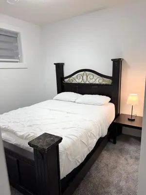a bedroom with a large bed with a black headboard at Charming Basement Suite in Edmonton