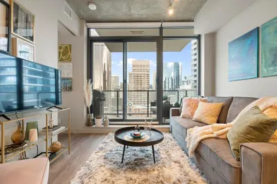 a living room with a couch and a large window at Stylish Condo with Exclusive Rooftop Pool in Calgary