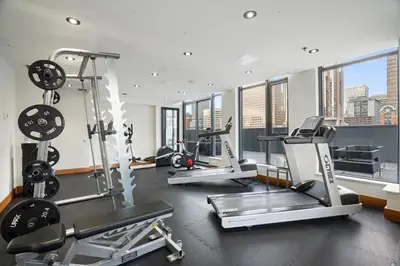 a gym with several treadmills and elliptical machines at Stylish Condo with Exclusive Rooftop Pool in Calgary