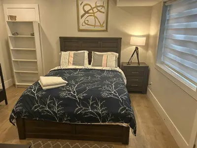 a bedroom with a bed with a black comforter at Spacious one Bedroom Suite Right in Downtown ! in Maple Ridge District Municipality