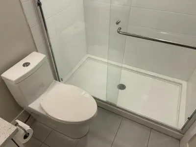 a white bathroom with a shower and a toilet at Spacious one Bedroom Suite Right in Downtown ! in Maple Ridge District Municipality