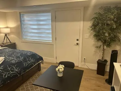 a bedroom with a bed and a table with flowers on it at Spacious one Bedroom Suite Right in Downtown ! in Maple Ridge District Municipality