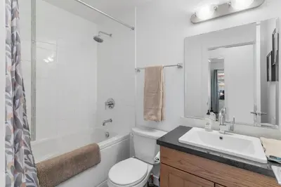 a white bathroom with a sink and a tub and a toilet at Luxury Lake View Condo in West Kelowna, 5 Star Resort with Pool, Hot Tub and Gym in West Kelowna