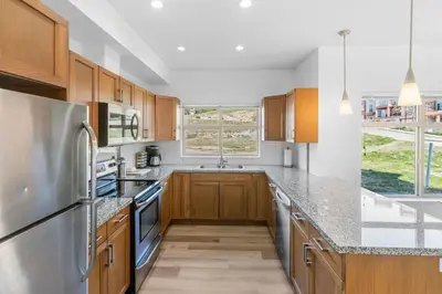 a kitchen with wooden cabinets and a stainless steel refrigerator at Luxury Lake View Condo in West Kelowna, 5 Star Resort with Pool, Hot Tub and Gym in West Kelowna