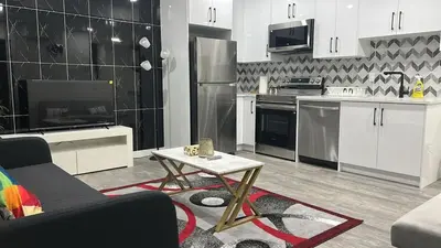 a kitchen with white cabinets and a table in a living room at Haven Lodge, 2BR Brand New Basement Suite in Calgary