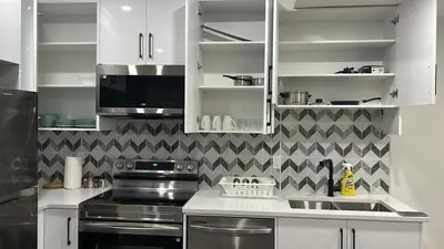 a kitchen with white cabinets and a stove top oven at Haven Lodge, 2BR Brand New Basement Suite in Calgary