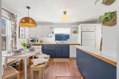 a kitchen with blue and white cabinets and a table at Bluebird 3 Bedroom Home in the Heart of Drumheller in Drumheller