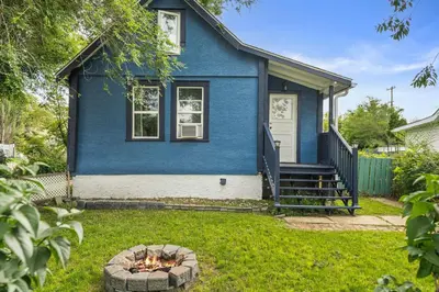 a blue house with a fire pit in the yard at Bluebird 3 Bedroom Home in the Heart of Drumheller in Drumheller