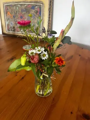 a vase filled with flowers on a wooden table at Beautiful Vancouver Cedar Cottage House in Vancouver