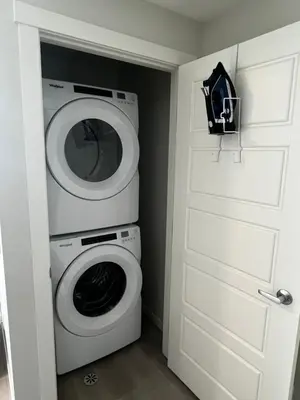 a laundry room with a washing machine and a door at The Oasis-A New 1 bed suite in Livingston Calgary close to the Airport in Calgary