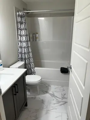a bathroom with a toilet and a shower curtain at The Oasis-A New 1 bed suite in Livingston Calgary close to the Airport in Calgary