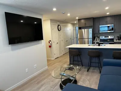 a kitchen with a large flat screen tv on a wall at The Oasis-A New 1 bed suite in Livingston Calgary close to the Airport in Calgary