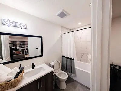 a bathroom with a sink and a toilet and a mirror at Coziest & Modern Basement Retreat East of Calgary in Chestermere