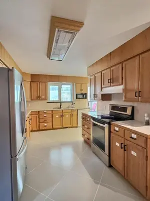 a kitchen with wooden cabinets and a stainless steel refrigerator at Vineyard Home Casa De Herrera in Keremeos