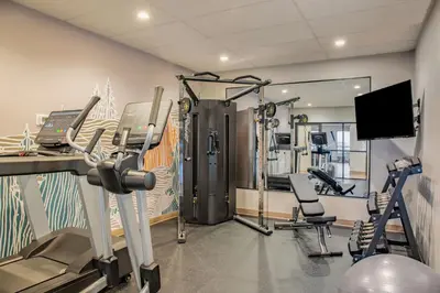 a gym with treadmills and machines in a room at Canalta Cochrane in Cochrane