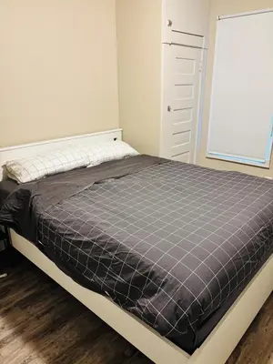 a bed in a bedroom with a gray mattress at Upper Floor 1 Bedroom Suite with Parking in Calgary