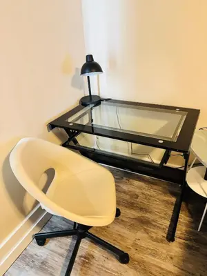 a glass desk with a chair and a lamp at Upper Floor 1 Bedroom Suite with Parking in Calgary