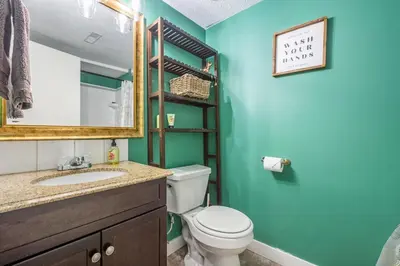 a bathroom with a toilet and a sink with a mirror at Modern 3 Bedroom Suite Near Downtown & Stampede Grounds in Calgary