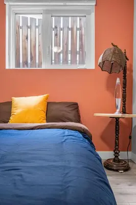 a bedroom with orange walls and a bed with a window at Modern 3 Bedroom Suite Near Downtown & Stampede Grounds in Calgary