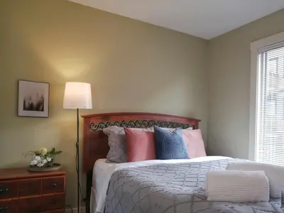a bedroom with a bed with colorful pillows and a lamp at Relaxing Mountain View Condo in Beautiful Radium in Radium Hot Springs