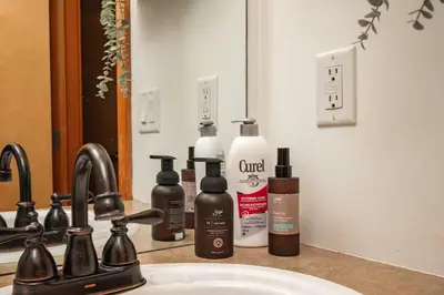 a bathroom counter with four bottles of soap and a sink at Rocky Mountain Oasis-Mountain View! in Canmore