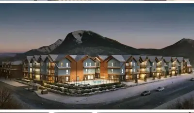 a large building with a mountain in the background at Sparrowhawk Mountain Resort in Dead Man's Flats