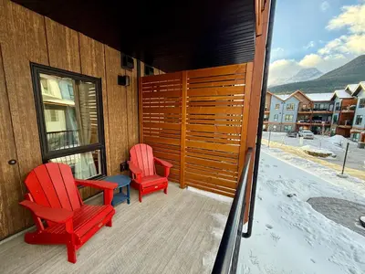 two red chairs and a table on a balcony at Sparrowhawk Mountain Resort in Dead Man's Flats