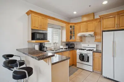 a kitchen with wooden cabinets and a white refrigerator at Bright and Comfy 3BR Home Ideal for Families in Vancouver