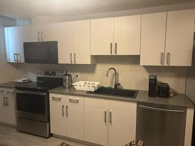 a kitchen with white cabinets and a sink and a microwave at Spacious 2BR Suite - SW Edmonton in Edmonton