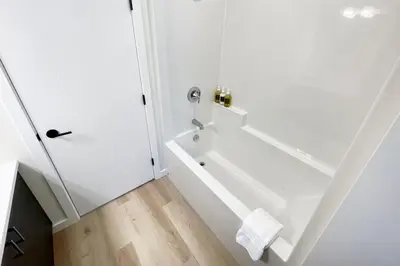 a white bathroom with a tub and a toilet at Aurelia Guest Suite and Sauna in Tofino