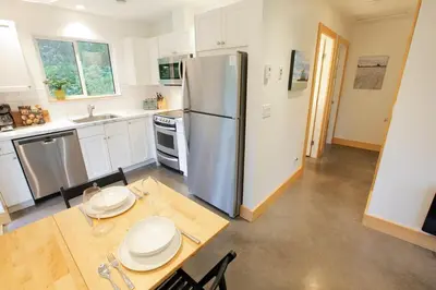 a kitchen with a stainless steel refrigerator and a table at Tidal Retreat Cabin in Tofino