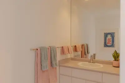 a bathroom with a sink and a mirror and towels at The Cougar Den in Tofino