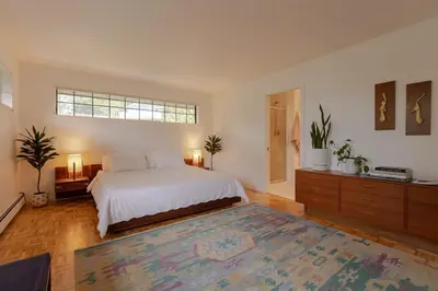 a bedroom with a white bed and a large rug at The Cougar Den in Tofino
