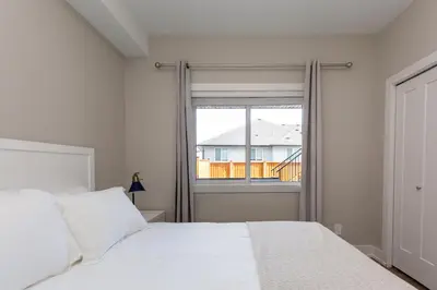 a bedroom with a white bed and a window at Cozy Garden Suite with Hot Tub and Perfectly Located in Goldstream Station